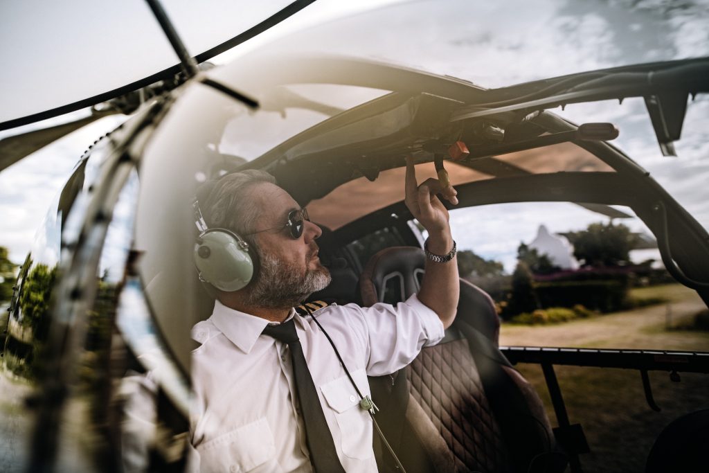 Pilot with headset starting the controls in the private helicopter. Helicopter pilot sitting in the cockpit.